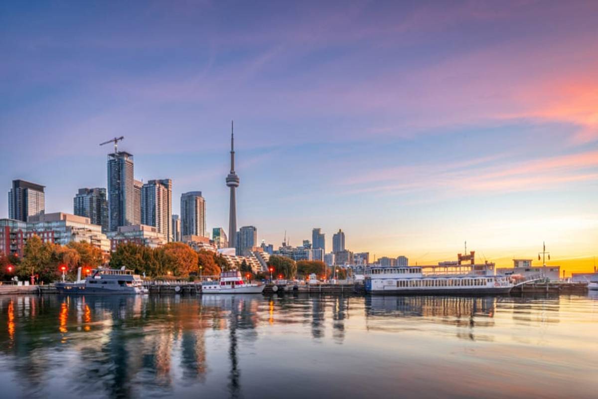 The Toronto skyline with the CN Tower reflected in the harbour at sunset, Canada