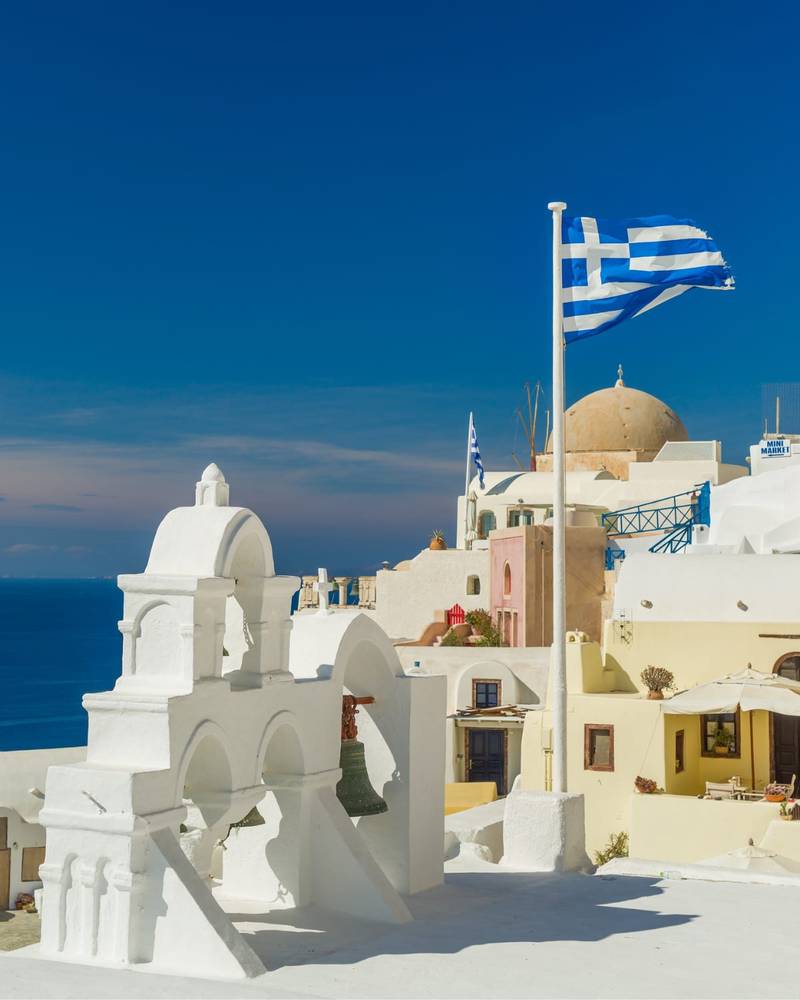 A whitewashed church and blue dome above the caldera in Santorini, Greece