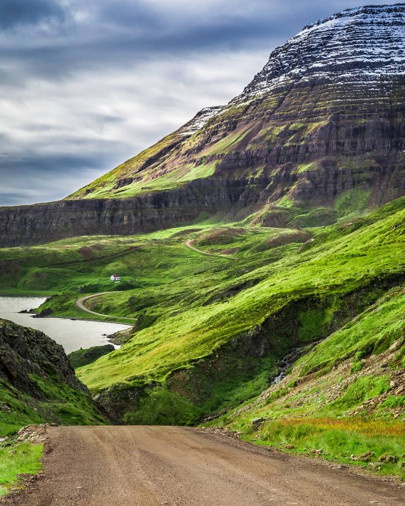 A lone house beneath towering fjord mountains, Iceland