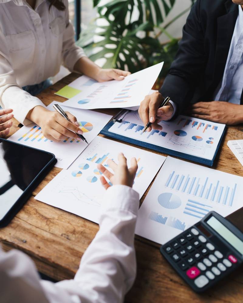 Zwei Berater prüfen Finanzdiagramme und Grafiken mit Stiften und einem Taschenrechner
