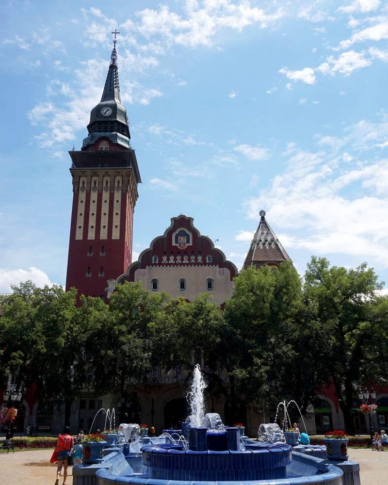 Der Jugendstil-Rathausturm über dem blau gefliesten Brunnen auf dem Hauptplatz, Subotica, Serbien