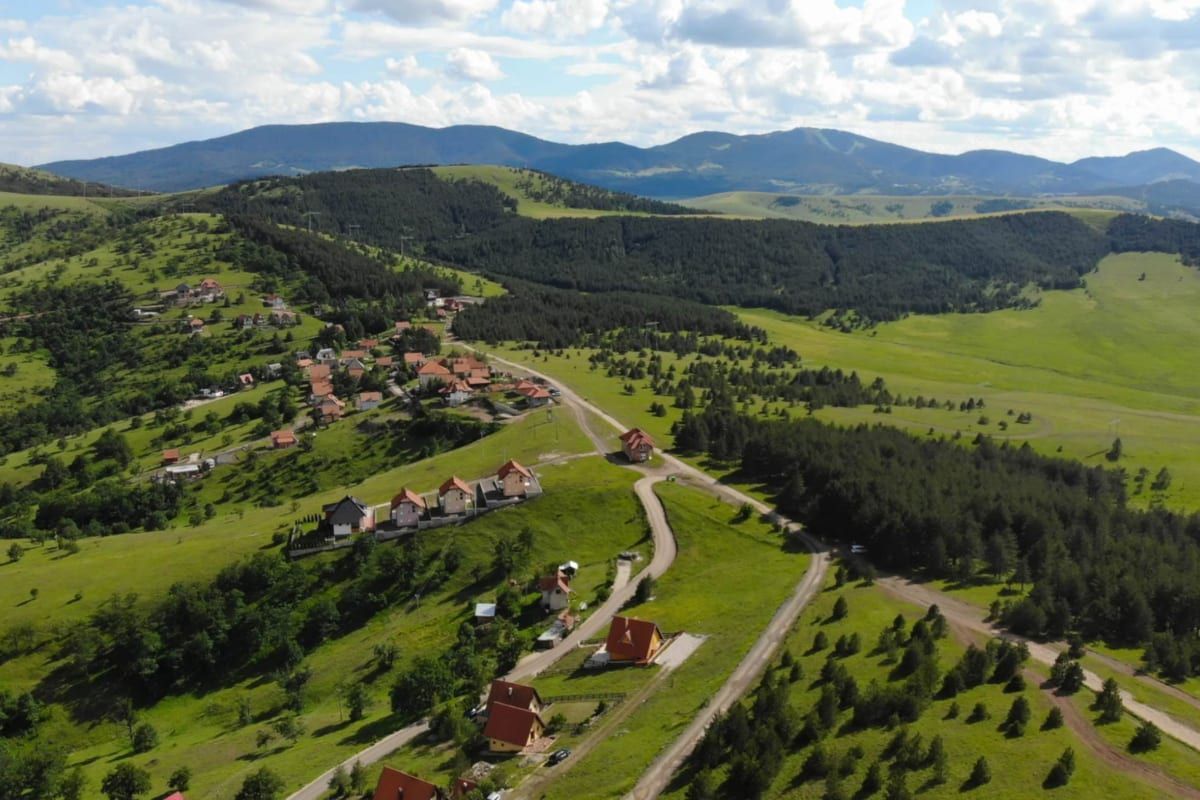 Scattered chalets and houses across green rolling hills and pine forest on the edge of Zlatibor.